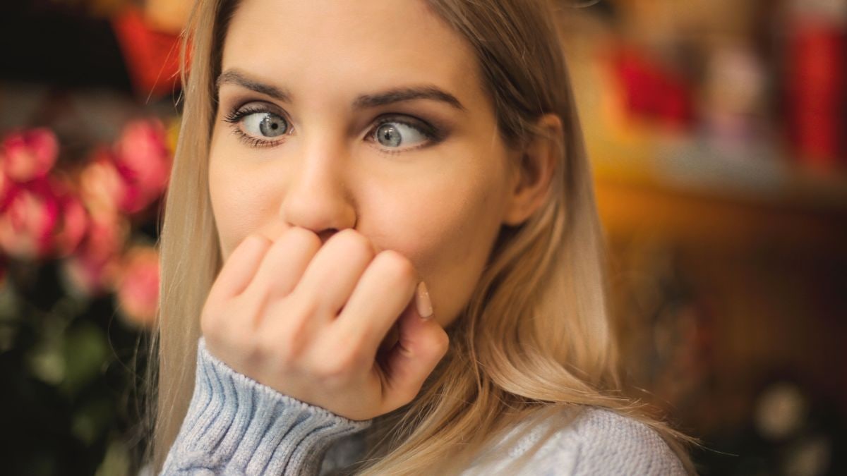 A blonde woman makes a silly face indoors, showcasing a playful and humorous expression.
